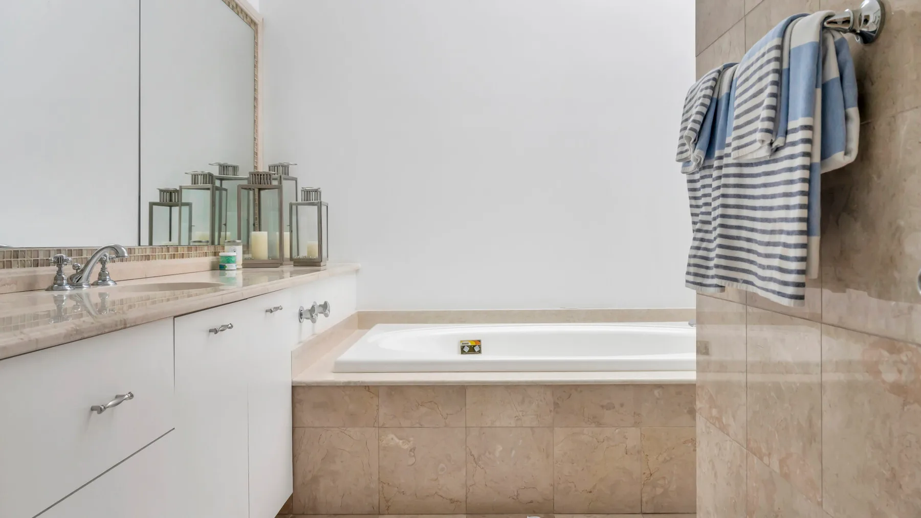 Un baño con una bañera empotrada y una toalla a rayas colgada cerca.