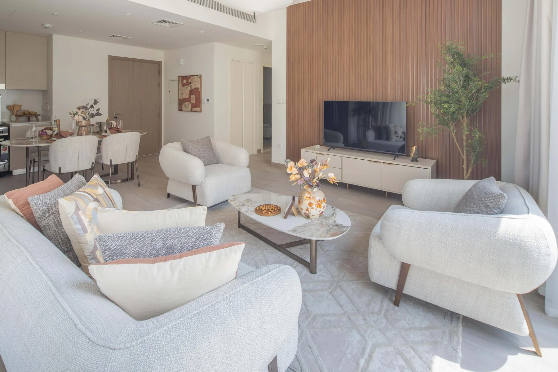A bright living room with seating around a coffee table and a television.