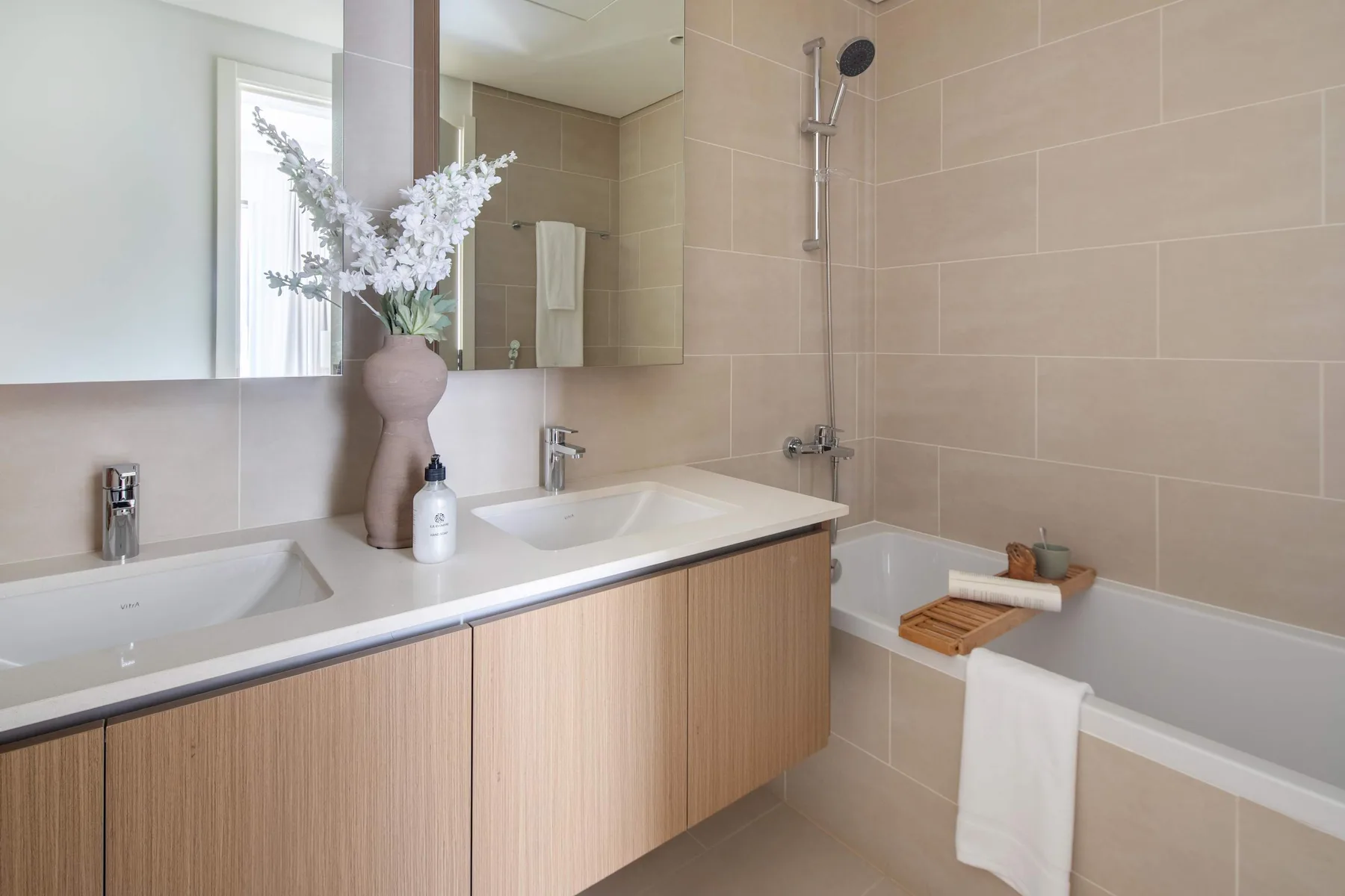 A bathroom with a long vanity and a bathtub beside the tiled shower.