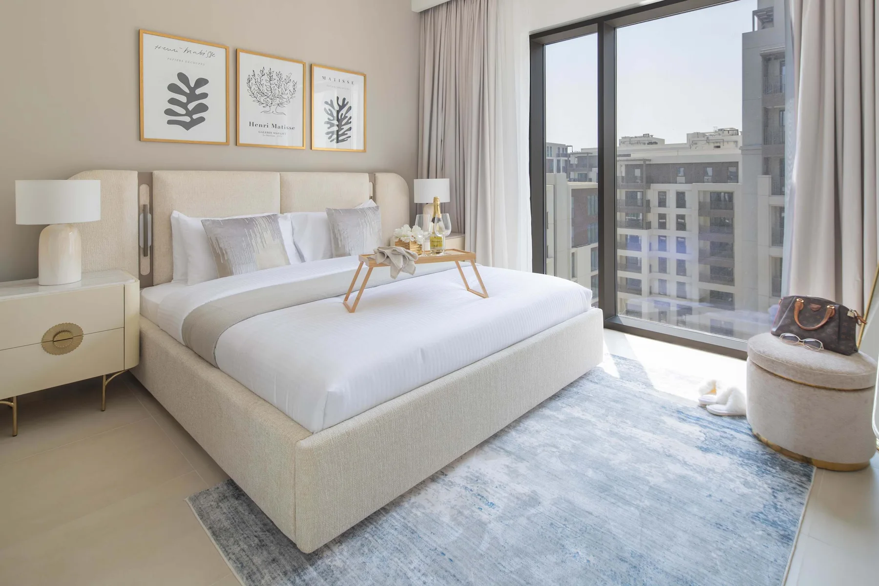 A bright bedroom with a neatly made bed beside a large window.