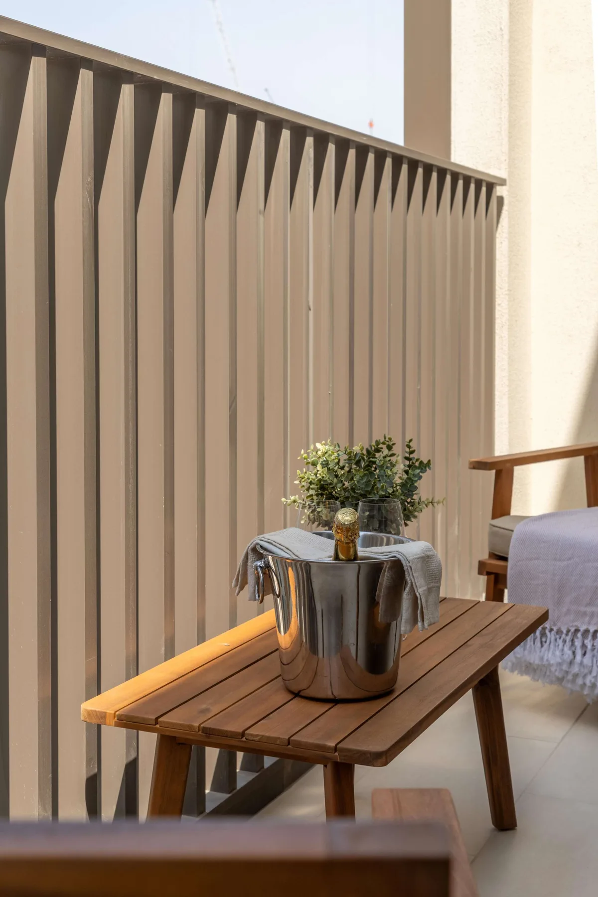 A small outdoor seating area with a wooden table and potted greenery.
