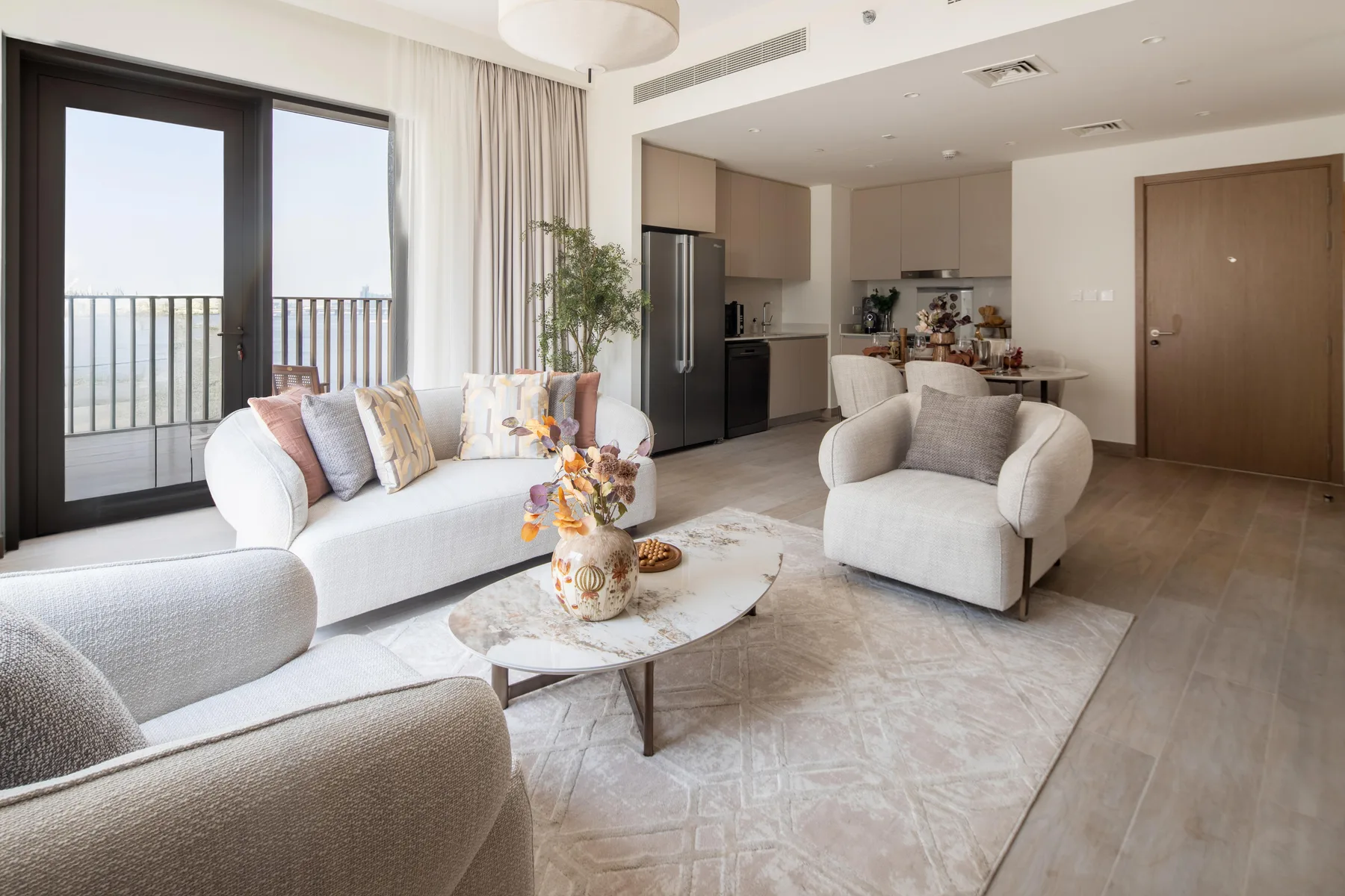 A bright living area with seating, a coffee table, and an open kitchen.