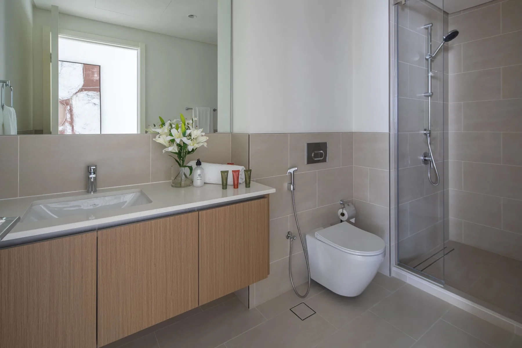 A modern bathroom with a long vanity and a glass-enclosed shower.