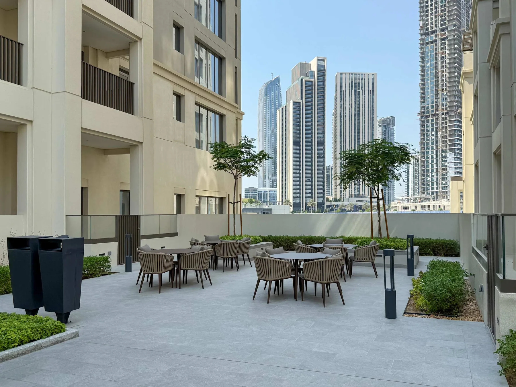 An outdoor seating patio between buildings, with tables and chairs overlooking city towers.