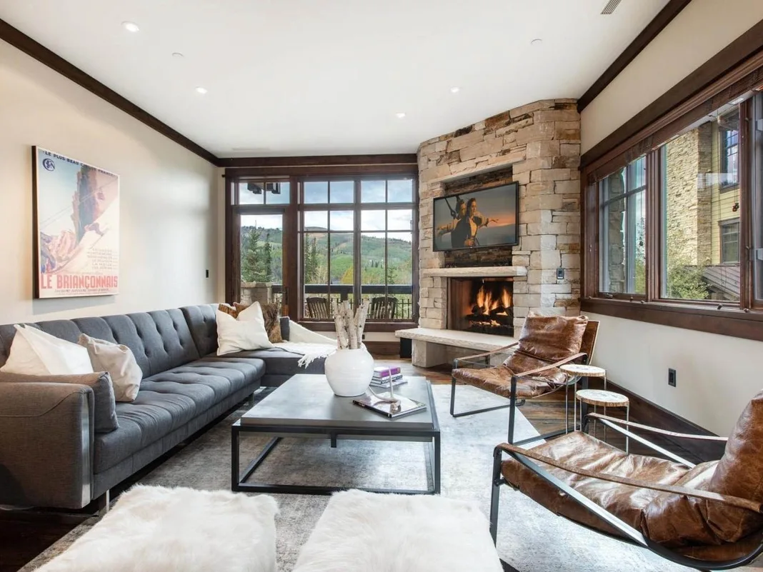 A living room with seating around a coffee table and a stone fireplace.