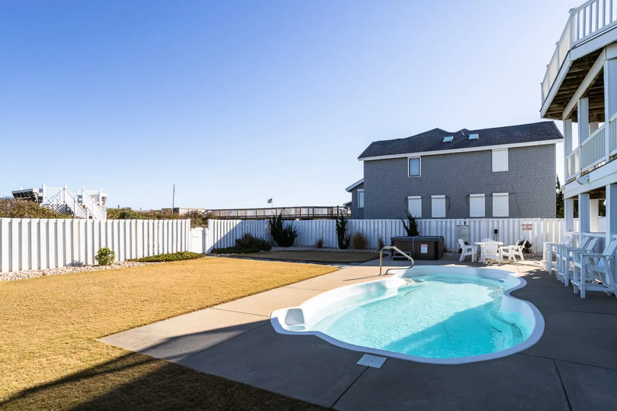 Una piscina al aire libre está en un patio cercado junto a edificios residenciales.