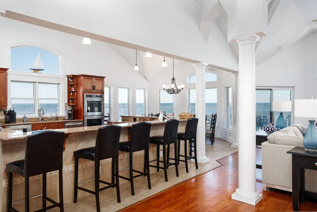 Una cocina abierta con comedor, una barra larga y vistas al mar.