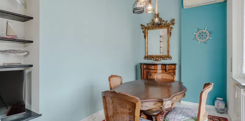A dining area with a wooden table, chairs, and a decorative wall mirror.