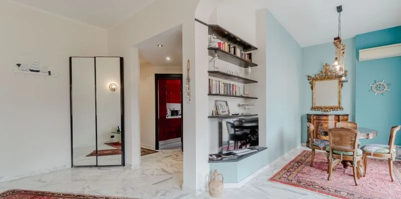 An interior room with a dining table, shelving, and a television.