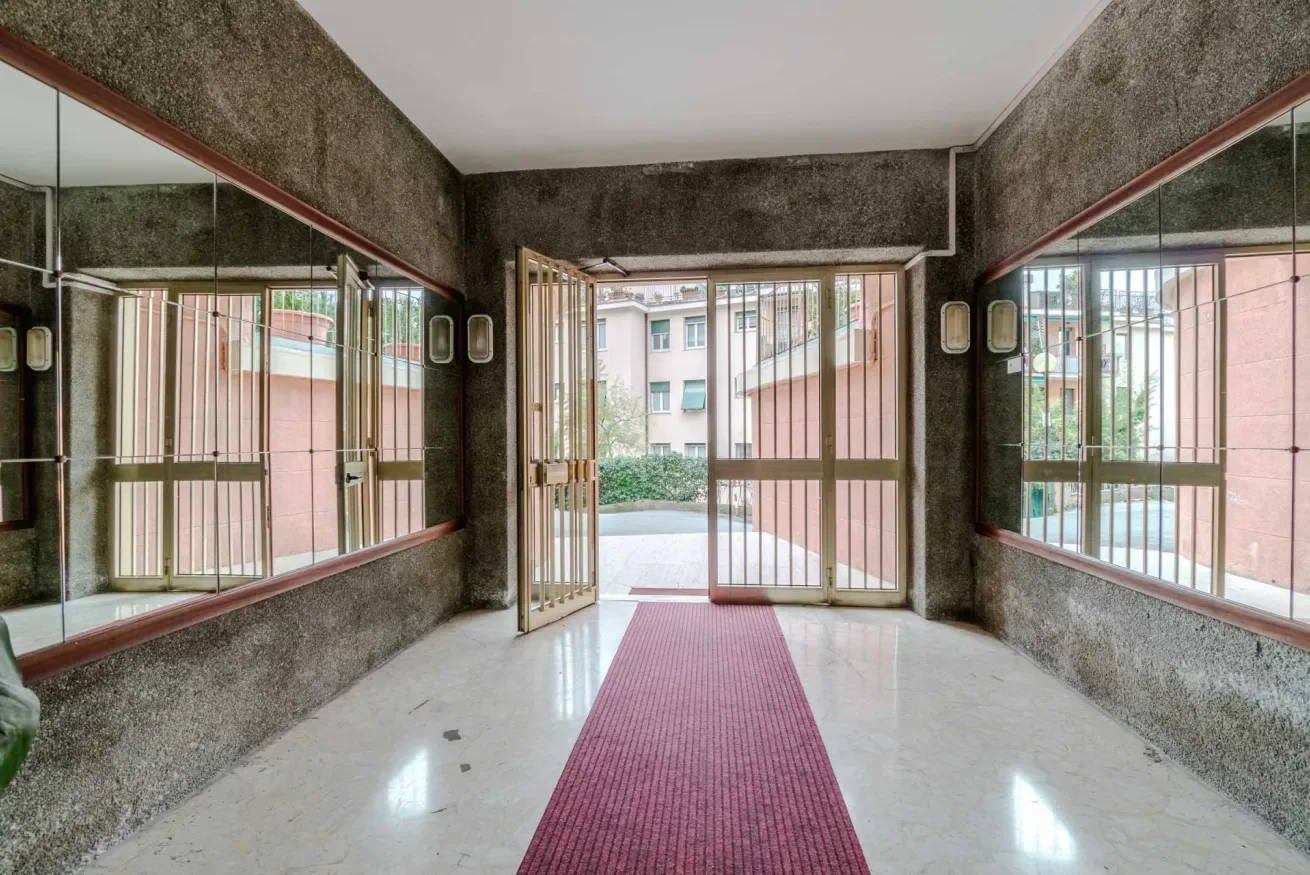 A building entrance hall with a red runner and large mirrored walls.