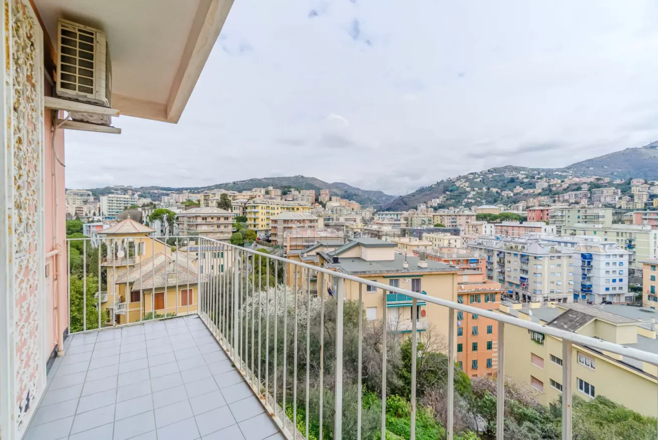 A balcony overlooks a hillside neighborhood of buildings.