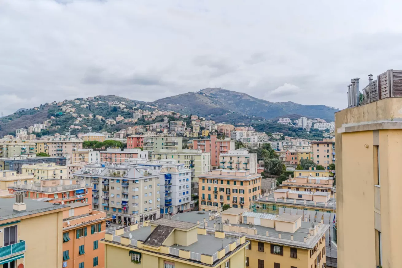 City buildings spread across a hillside beneath cloudy skies.