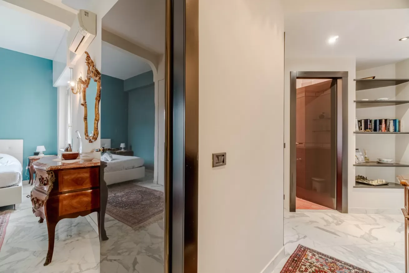 A bedroom with twin beds and a mirrored wardrobe beside an open doorway.