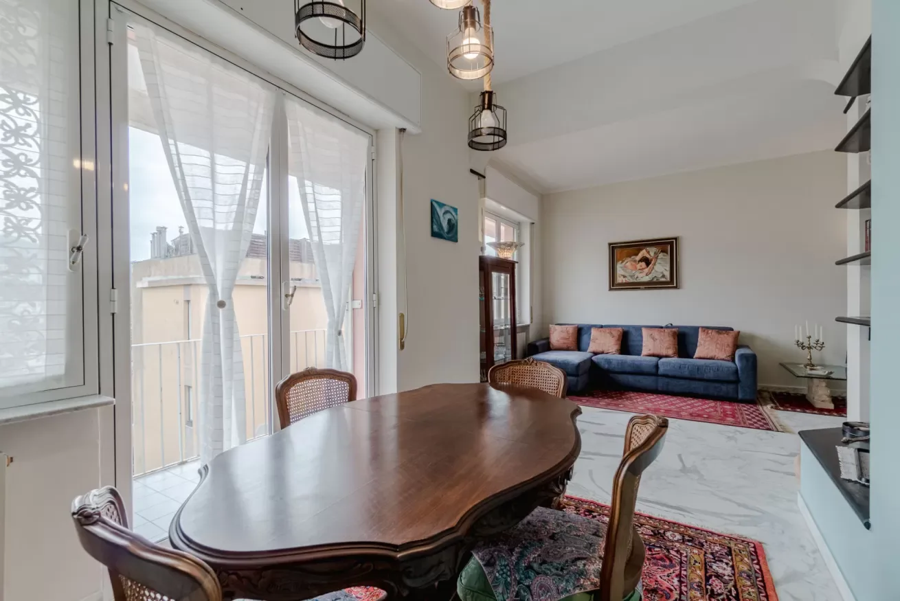 A bright living and dining area with a wooden table and blue seating.