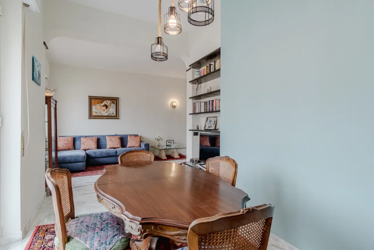 A living and dining room with a large wooden table and blue seating.