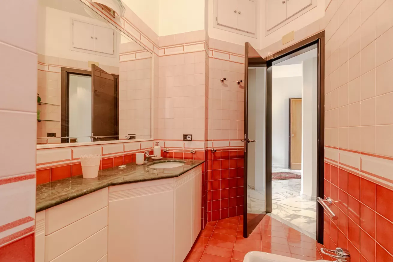 A tiled bathroom with a countertop, sink, and open doorway.
