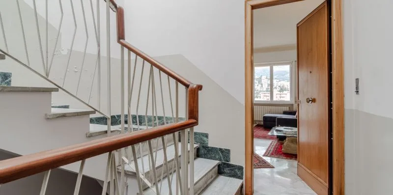 An interior staircase beside an open doorway leading into a living area.