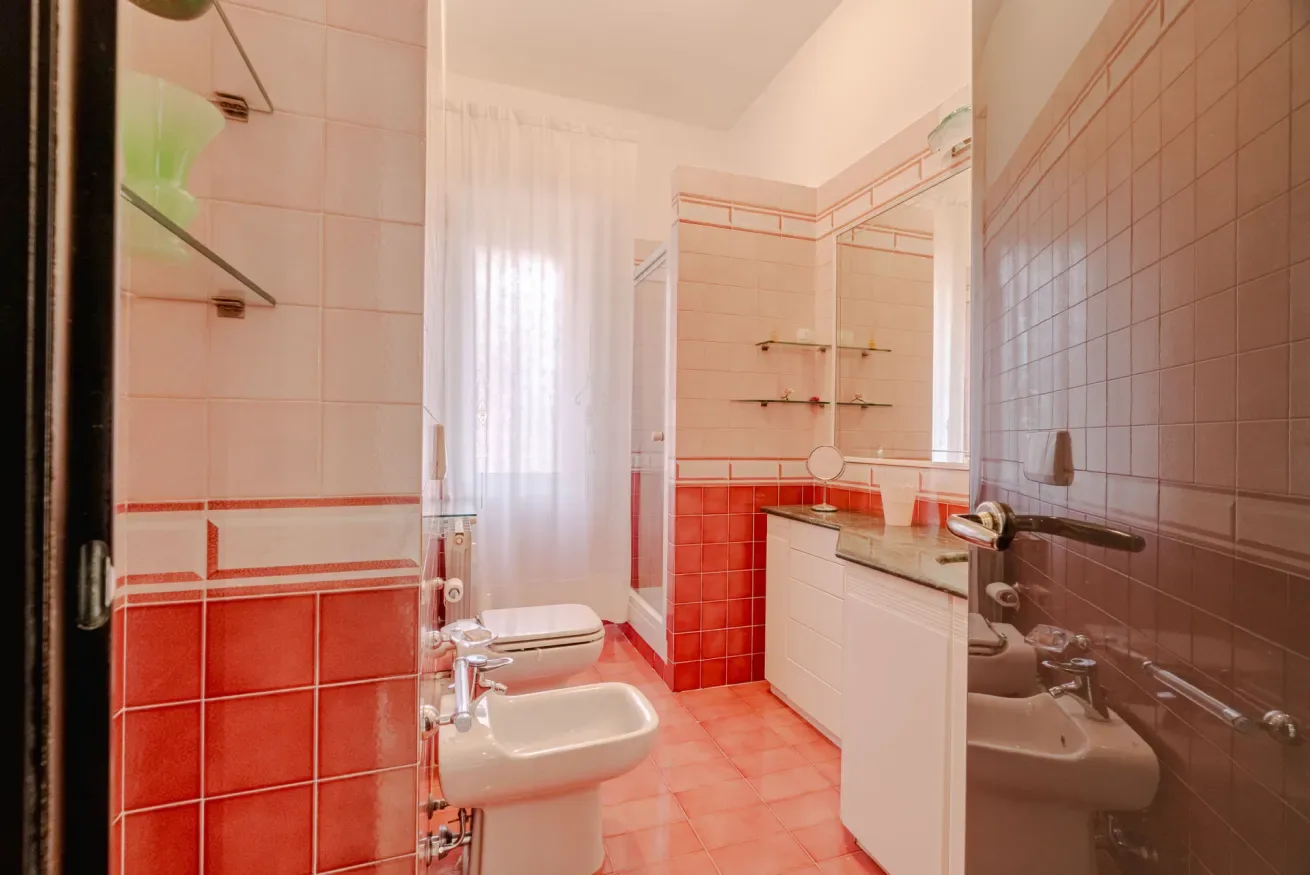 A tiled bathroom with a sink, toilet, and glass shower enclosure.