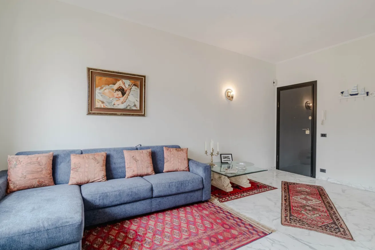 A living room with blue seating, patterned rugs, and framed artwork.