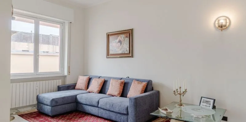 A living room with a gray sectional sofa, colorful cushions, and a glass coffee table.