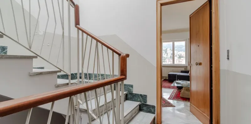 A staircase and railing lead to an open doorway into a living room.