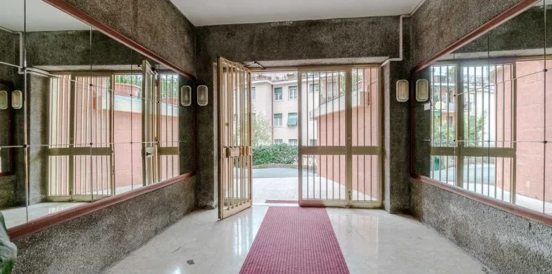 A building entrance opens onto a tiled walkway, with barred windows on either side.