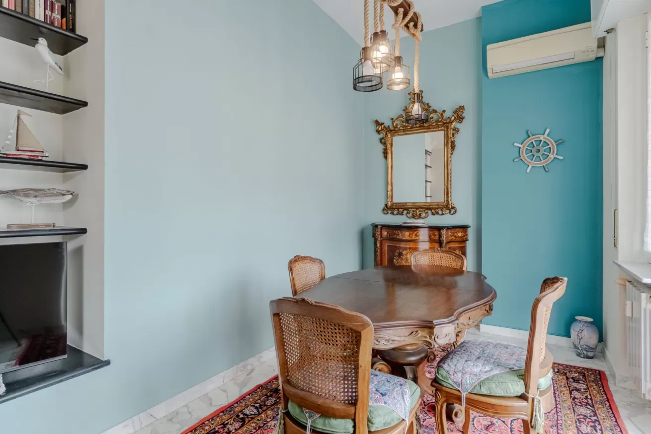 A dining area with a wooden table, chairs, and a mirror on the wall.