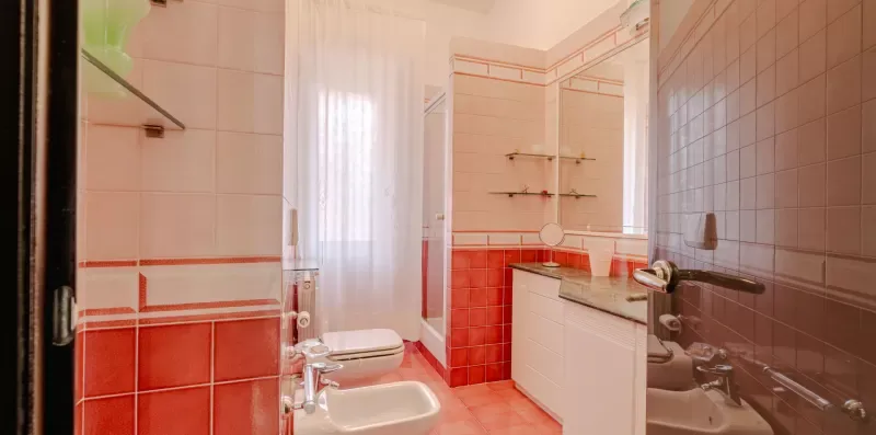 A tiled bathroom with a toilet, sink, and shower.