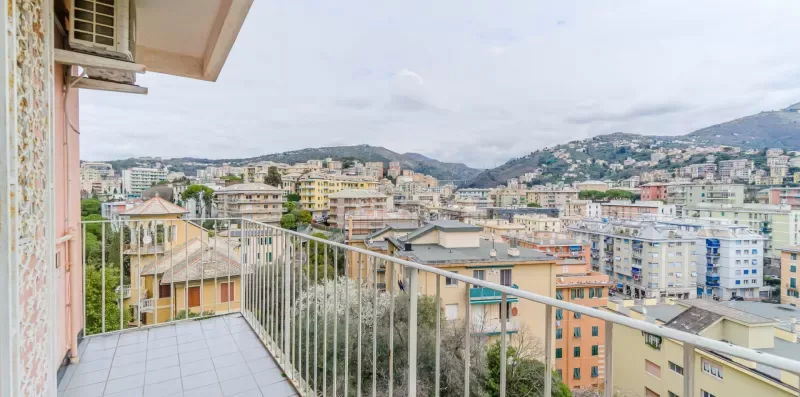 A balcony overlooks a cityscape of buildings and hills.