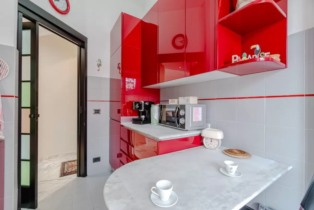 A kitchen with red cabinetry, appliances, and a rounded table.
