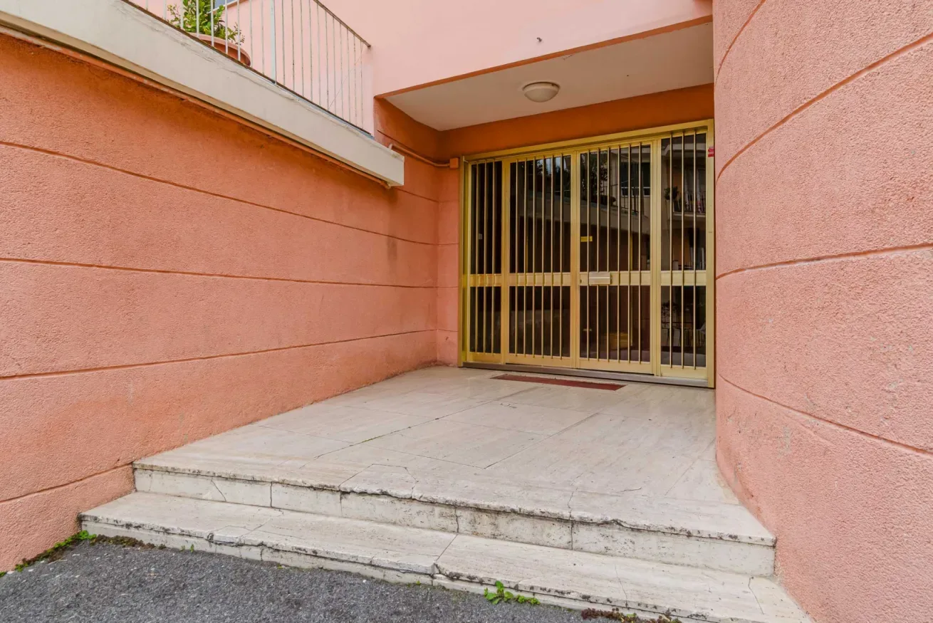 An exterior entrance with a tiled landing and metal security gate.
