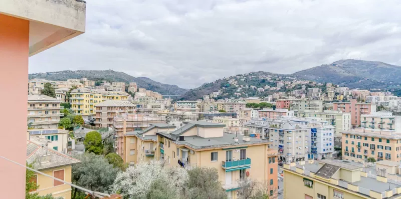 A hillside cityscape with closely spaced apartment buildings beneath cloudy skies.