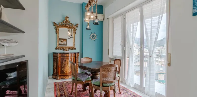 A bright dining area with a wooden table beside tall windows.