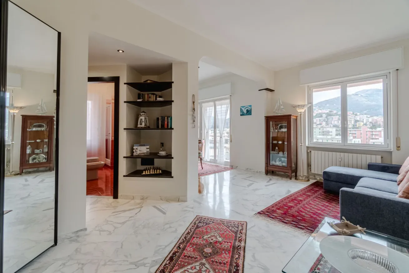 A bright living room with marble flooring, rugs, and a large window overlooking the city.