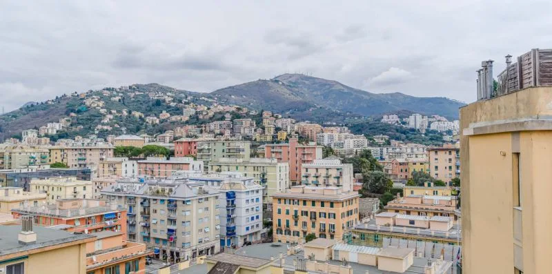 A cityscape of buildings spreads across the valley beneath a mountain.