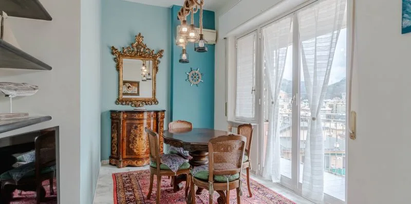 A dining area with a wooden table and chairs beside large windows.