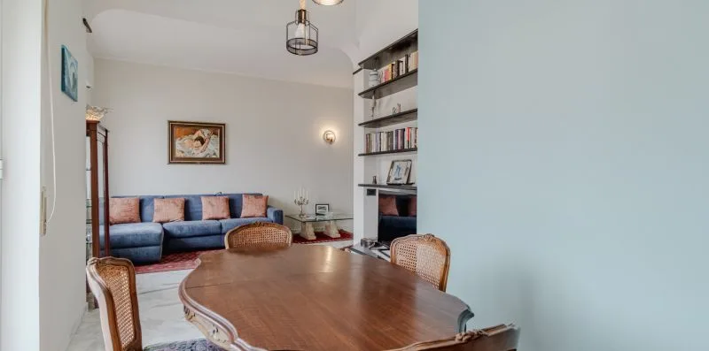 A living and dining area with a wooden table, seating, and wall shelves.
