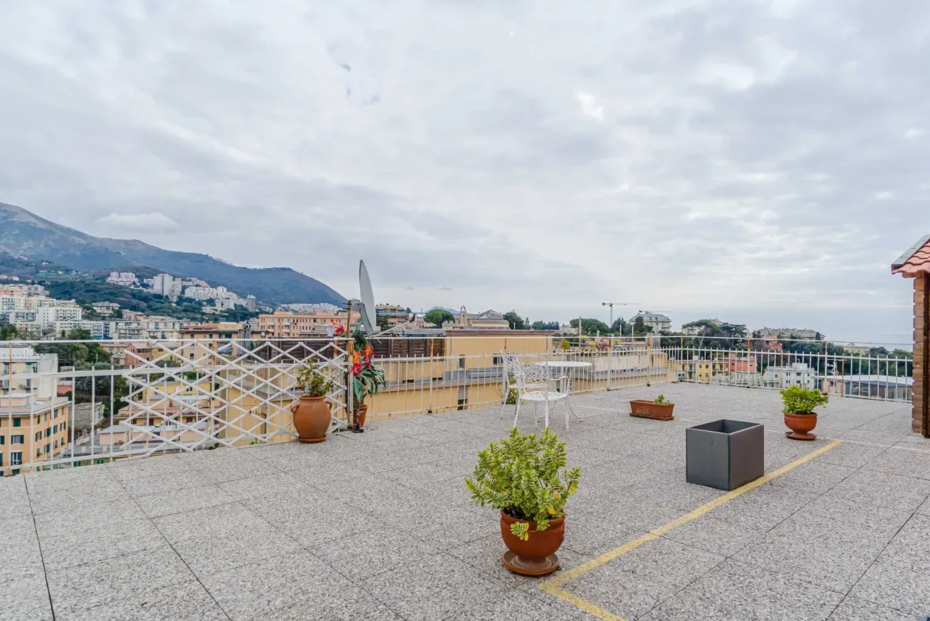 A spacious rooftop terrace overlooks nearby buildings and distant mountains.