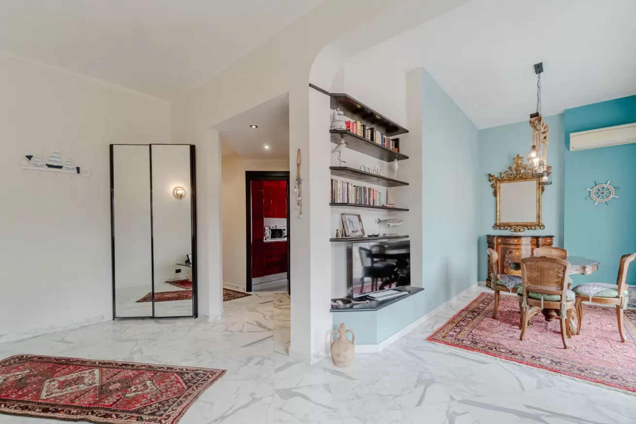 A bright living area with a television and a dining table on patterned rugs.
