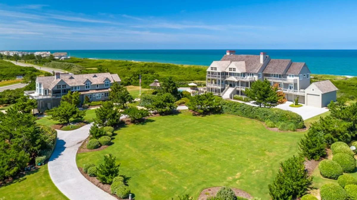 Coastal homes overlook a broad green lawn and the ocean.