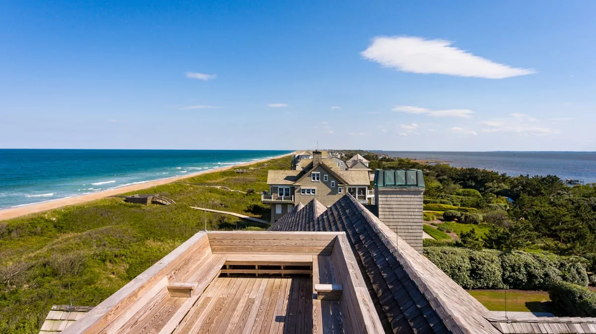 A rooftop deck overlooks a coastal landscape and the ocean.