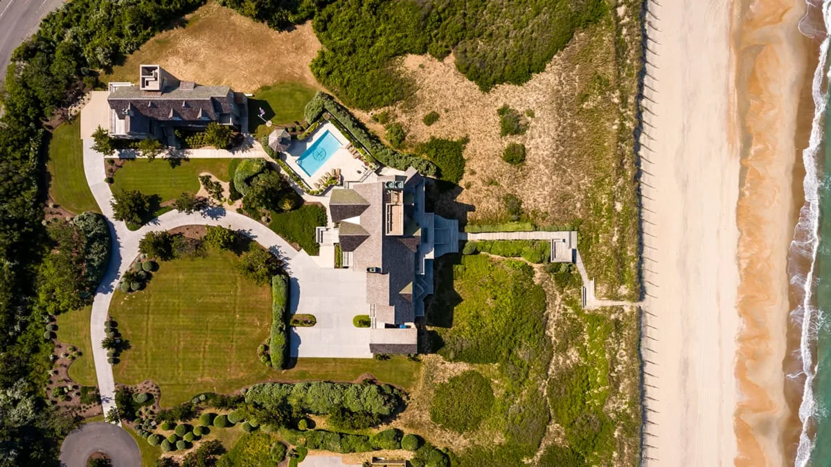 An aerial view shows a coastal property beside a sandy beach.