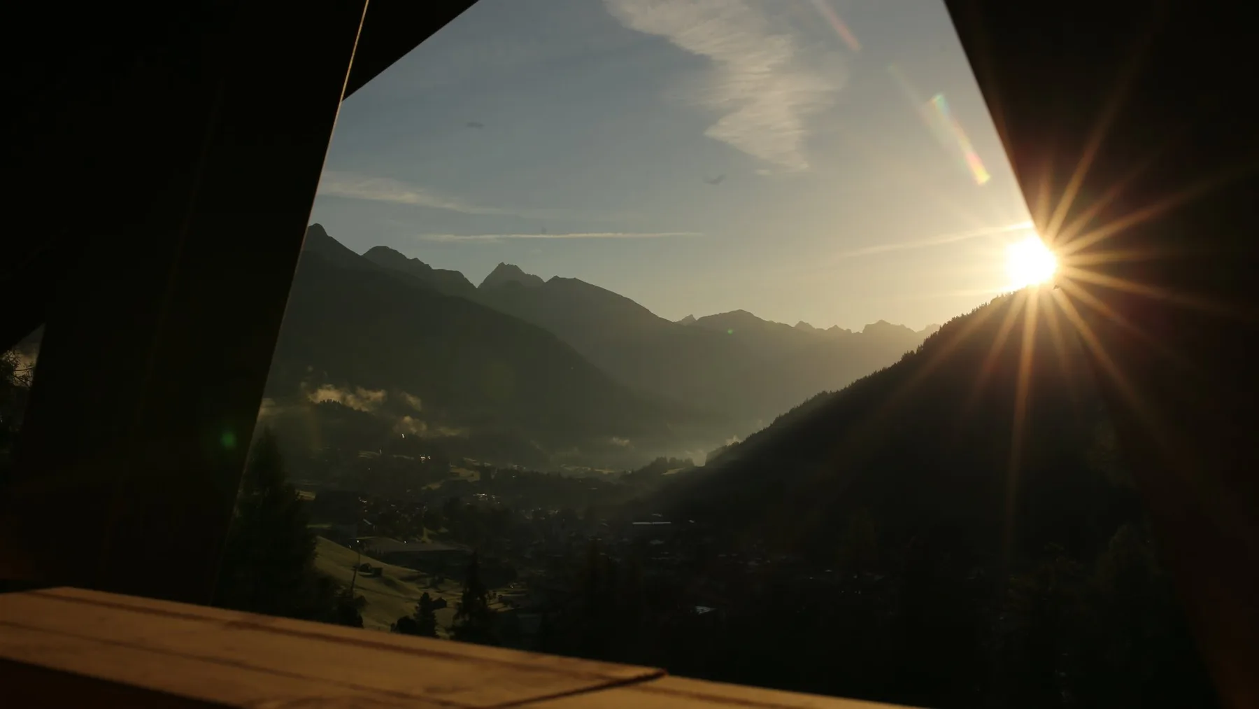 Sunrise over mountains framed by a wooden window