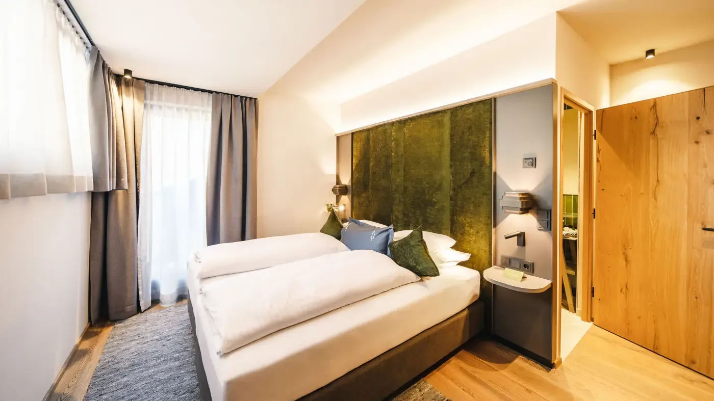 Bright hotel room with large bed and wood flooring