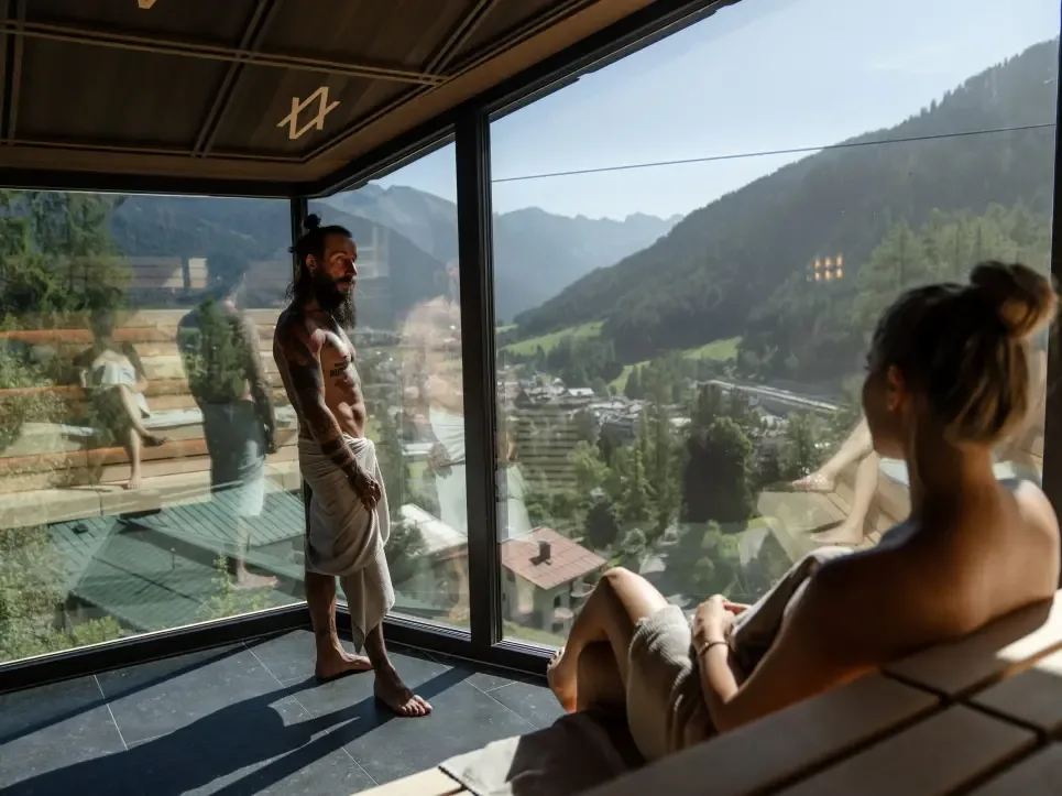 Guests relaxing in a glass room with mountain views