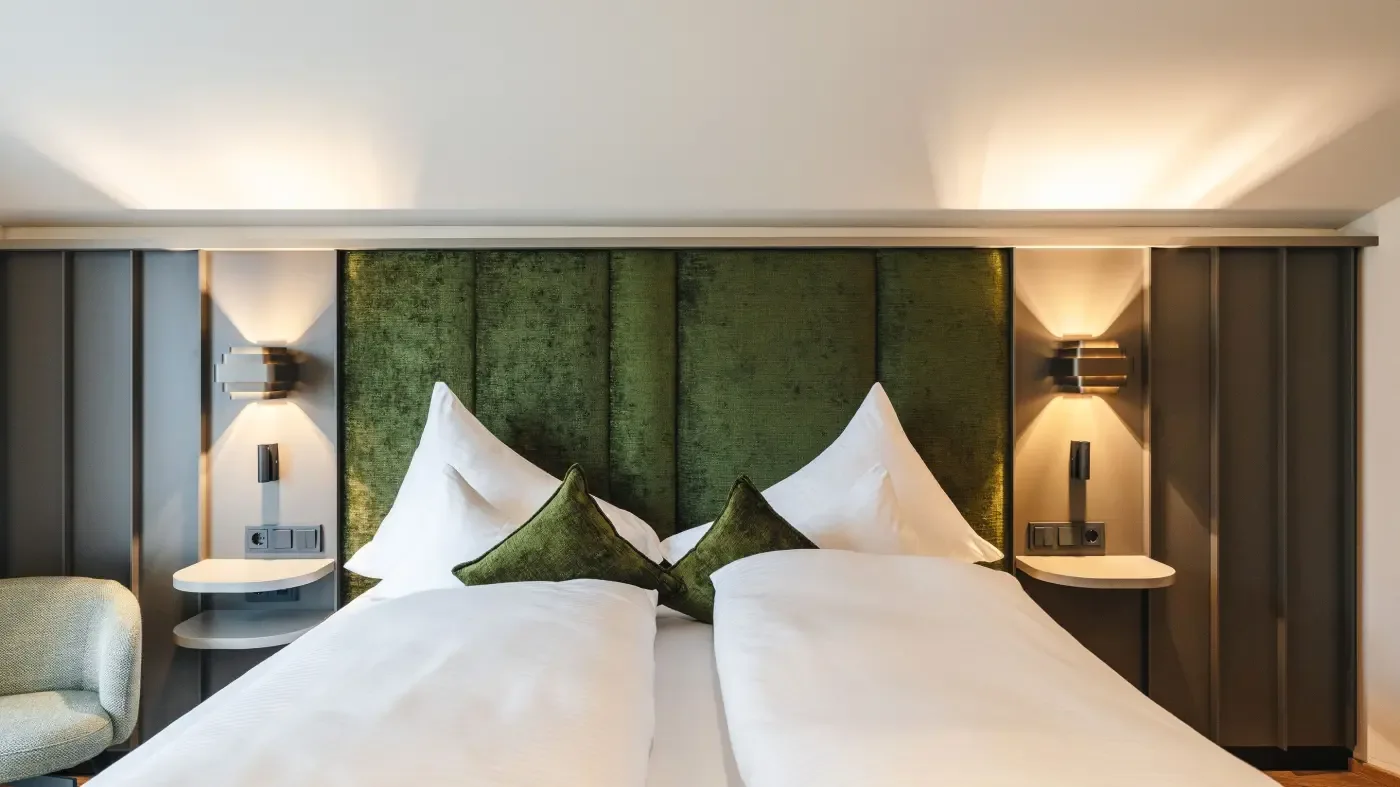 Double room with green headboard and modern lighting