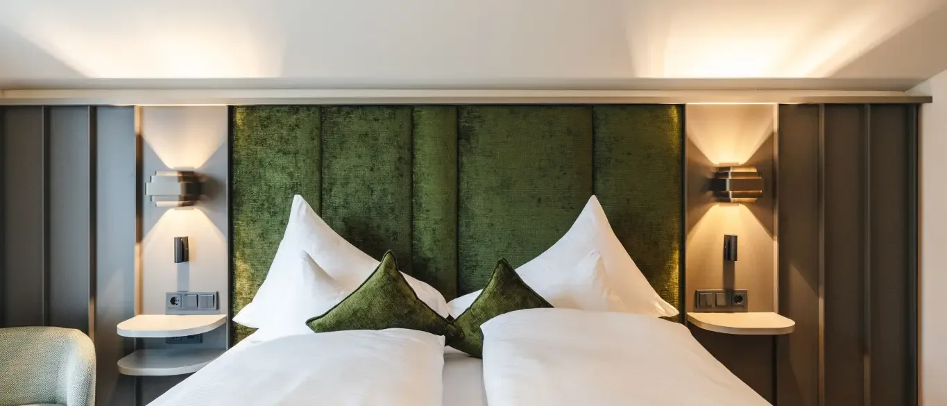 Double room with green headboard and modern lighting