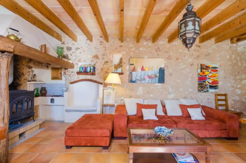 Una sala de estar rústica con asientos rojos, una chimenea y vigas de madera a la vista.