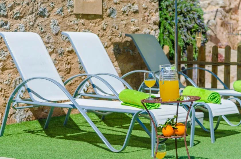 Asientos en un patio exterior con tumbonas reclinables y una mesa pequeña sobre césped artificial.
