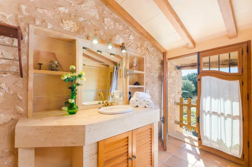 Un lavabo de baño con espejo y una puerta de vidrio con cortina que da a un balcón.